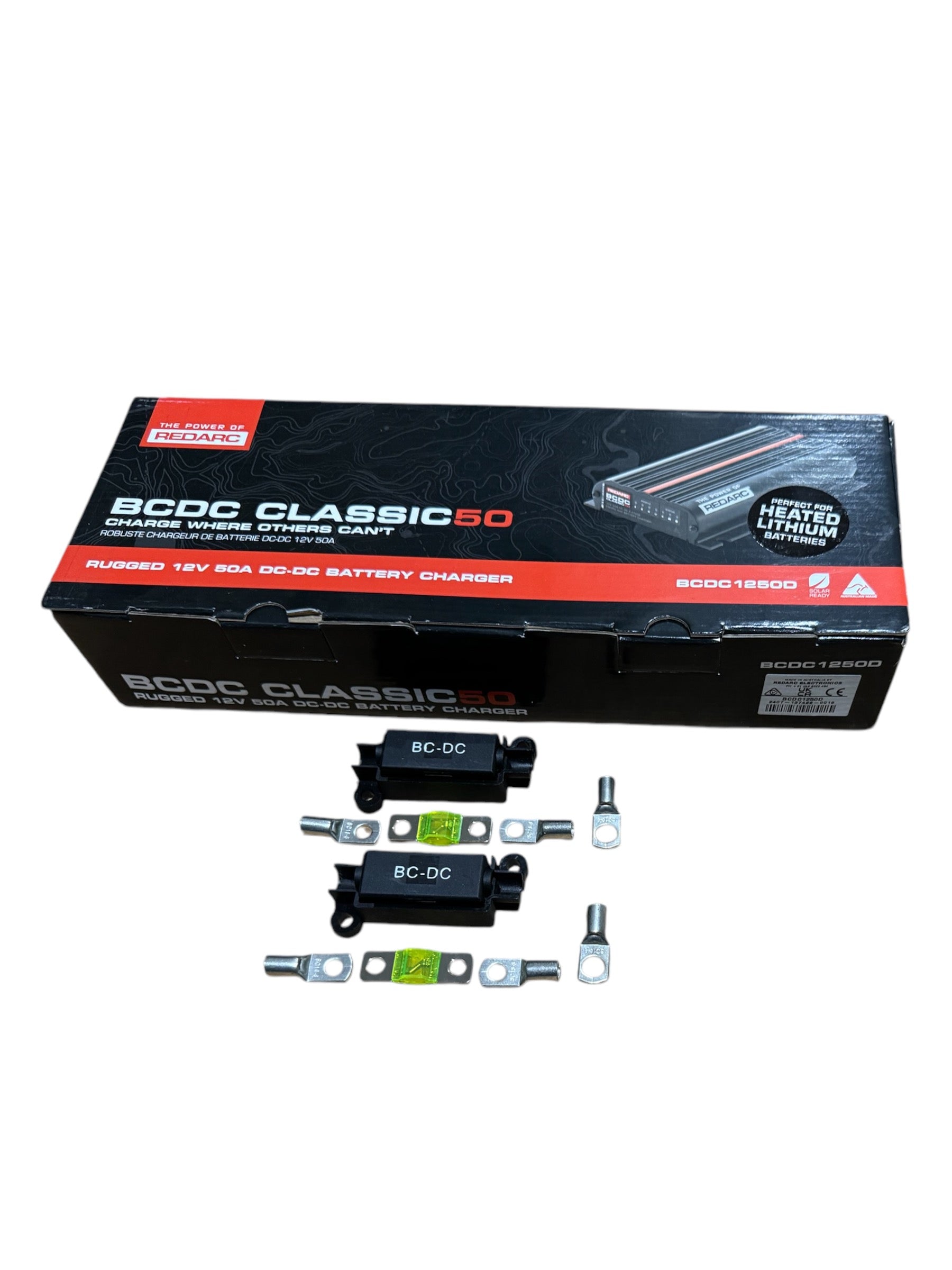 RedArc BCDC1250D in-vehicle dual battery charger kit with components laid out next to the packaging box labeled with BCDC Midi Fuse Kit.