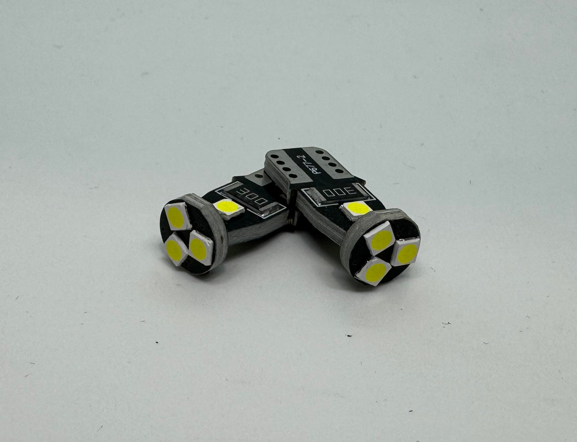 Two LED number plate globes with a bright white light visible through the clear part of the bulbs.