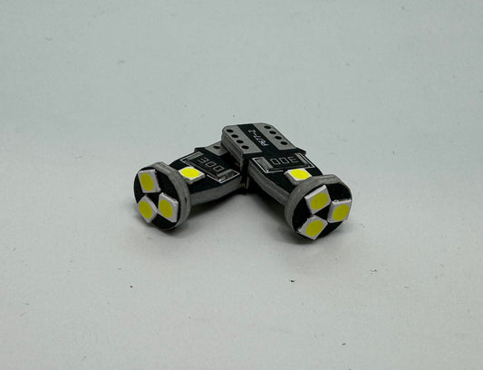 Two LED number plate globes with a bright white light visible through the clear part of the bulbs.
