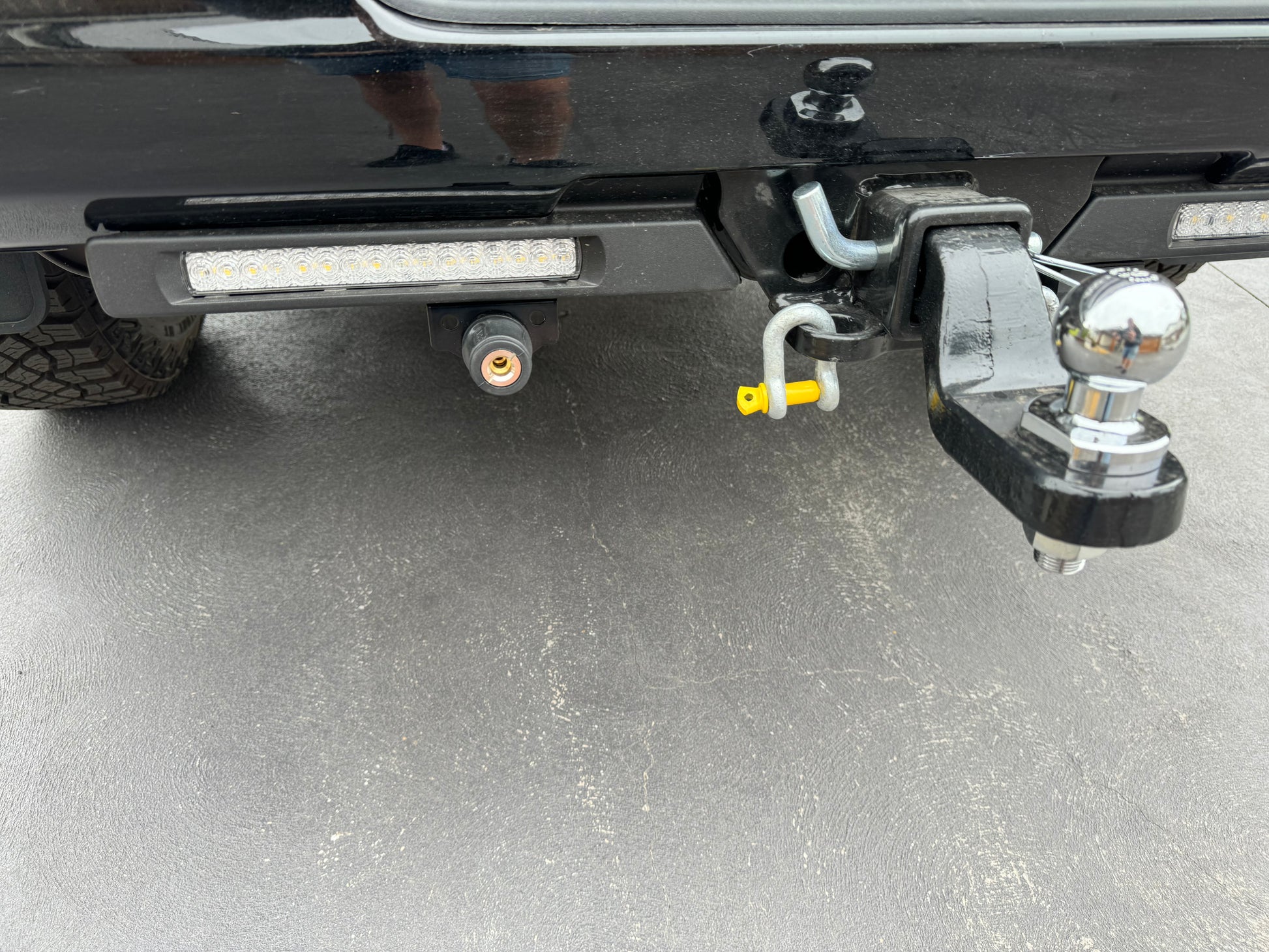 The image shows a close-up of the ARB Air Compressor Coupling Bracket mounted on the rear of a vehicle, with LED lights visible above it.