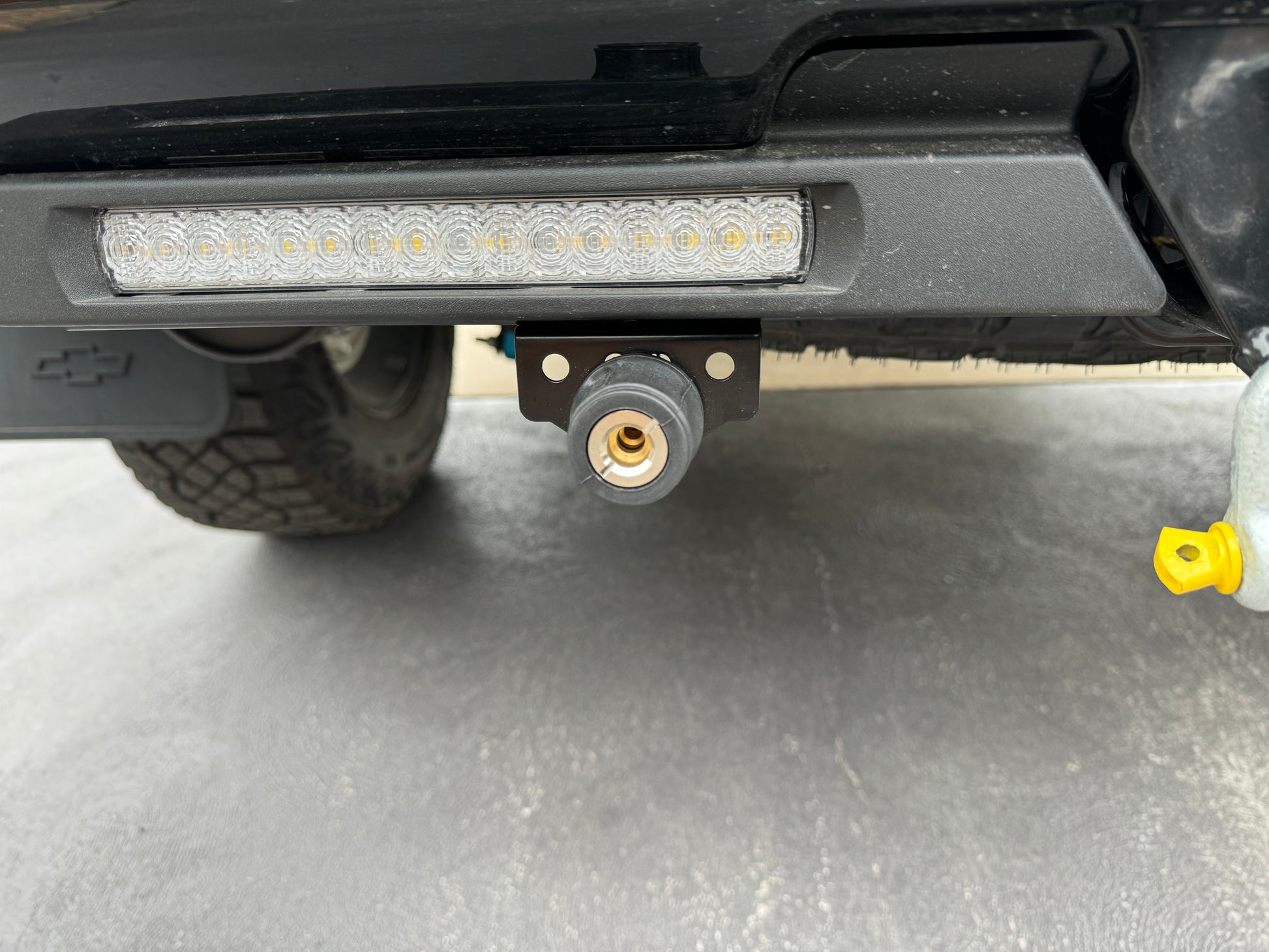 The image shows a close-up of the ARB Air Compressor Coupling Bracket mounted on the rear of a vehicle, with LED lights visible above it.
