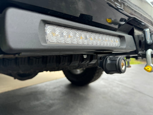 The image shows a close-up of the ARB Air Compressor Coupling Bracket mounted on the rear of a vehicle, with LED lights visible above it.
