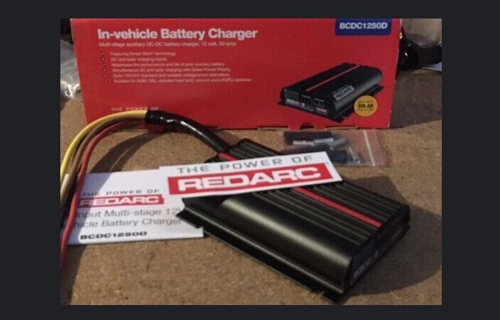 RedArc BCDC1250D in-vehicle dual battery charger kit with components laid out next to the packaging box labeled with BCDC Midi Fuse Kit.