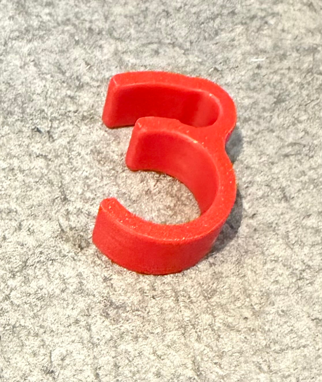 A bright red plastic ring-shaped component easy clip-on to lawn mower handle bar to hold brake lever
