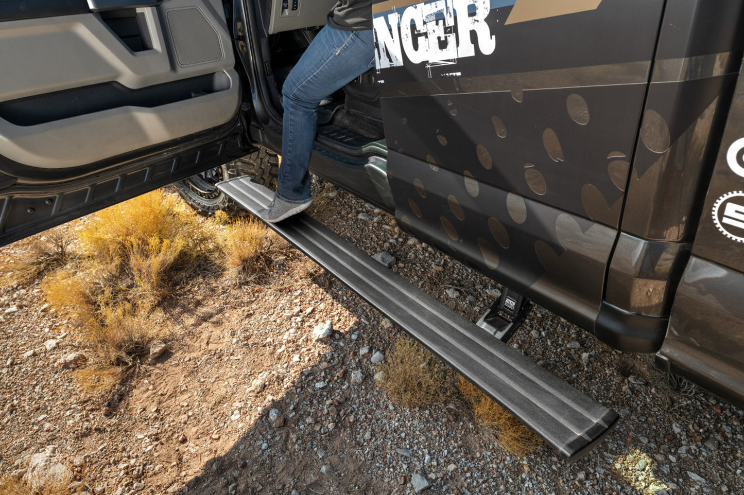 Person using a running board to enter a vehicle on a rugged terrain