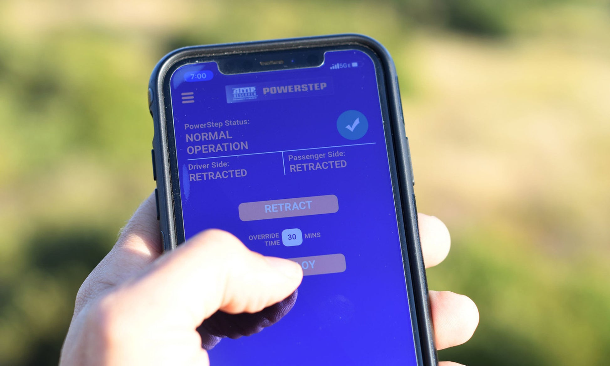 Hand holding a smartphone displaying an app interface with a blue screen.