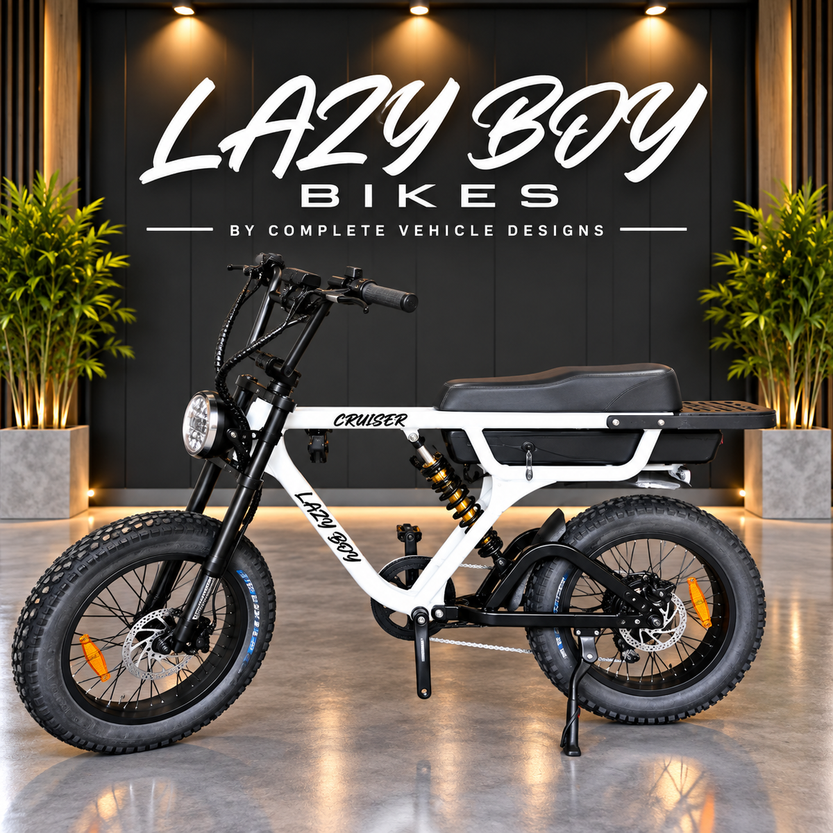 A white and black electric fat tire bike with a black saddle and rear cargo platform, displayed on a polished floor in front of a dark wall with the text 'LAZY BOY BIKES'.
